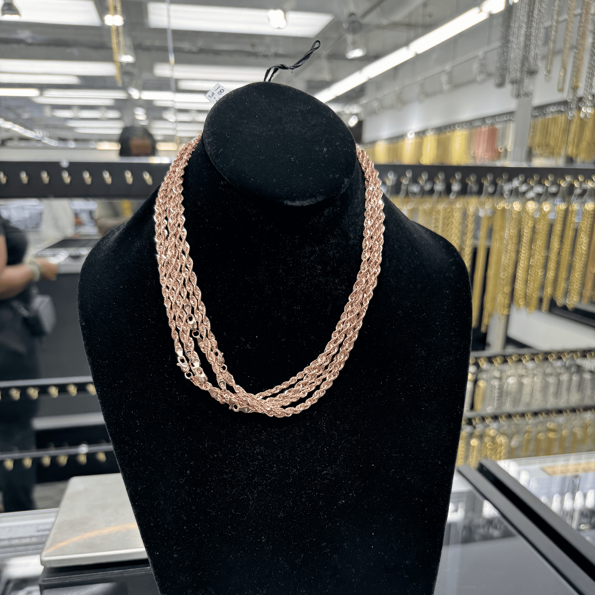 Rose gold necklace on a black mannequin bust in a store setting